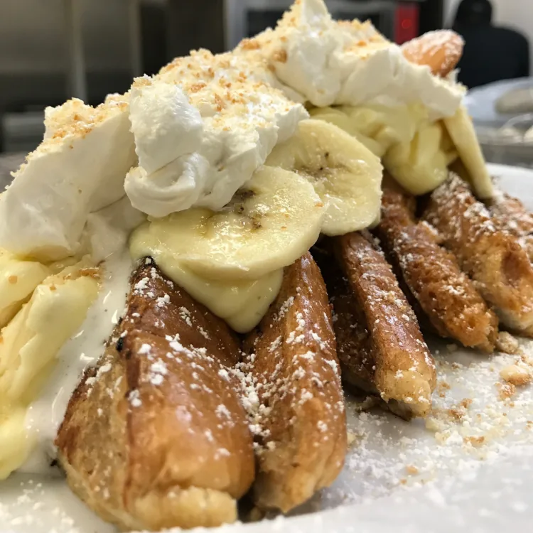 Banana rum French toast wedges topped with sliced bananas and whipped cream