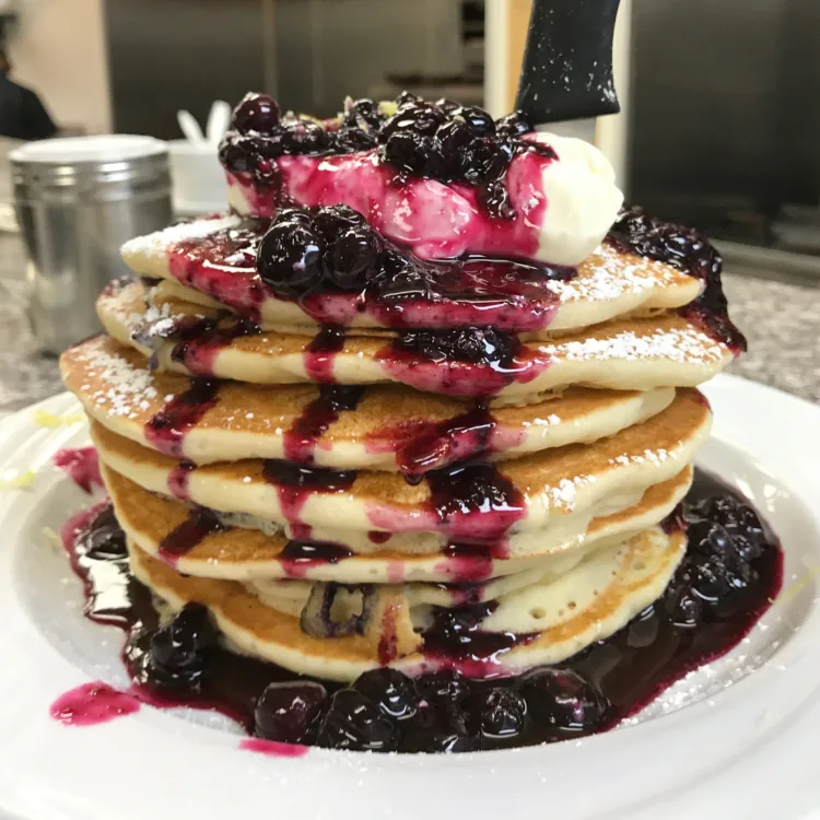 A tall stack of Peach’s pancakes with blueberry lemon topping